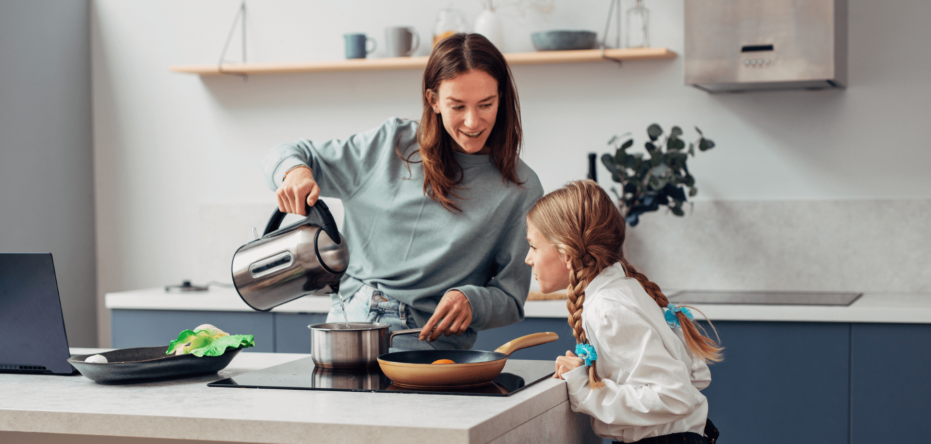 a woman pours water from a kettle with softened water into a saucepan while looking at her daughter